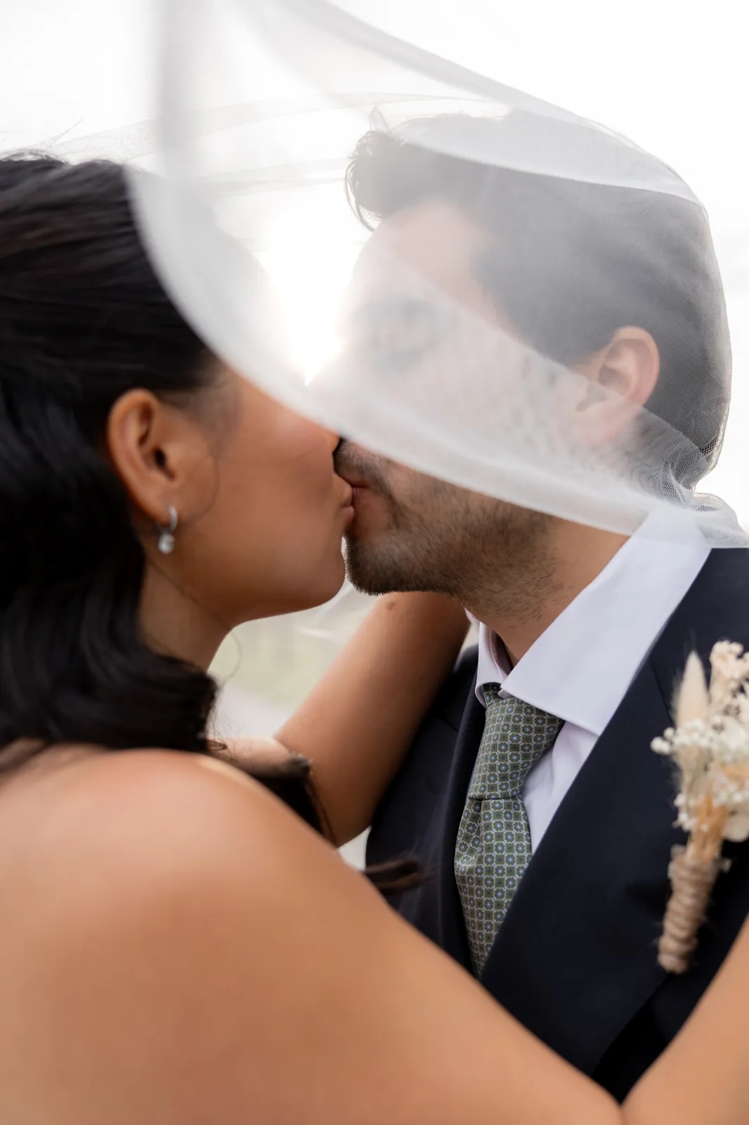 A couple sharing a kiss beneath the bride’s veil