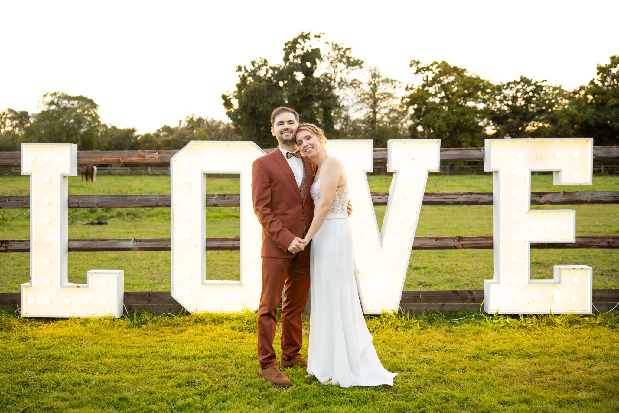 The newlyweds pose in front of large LOVE letters in the garden
