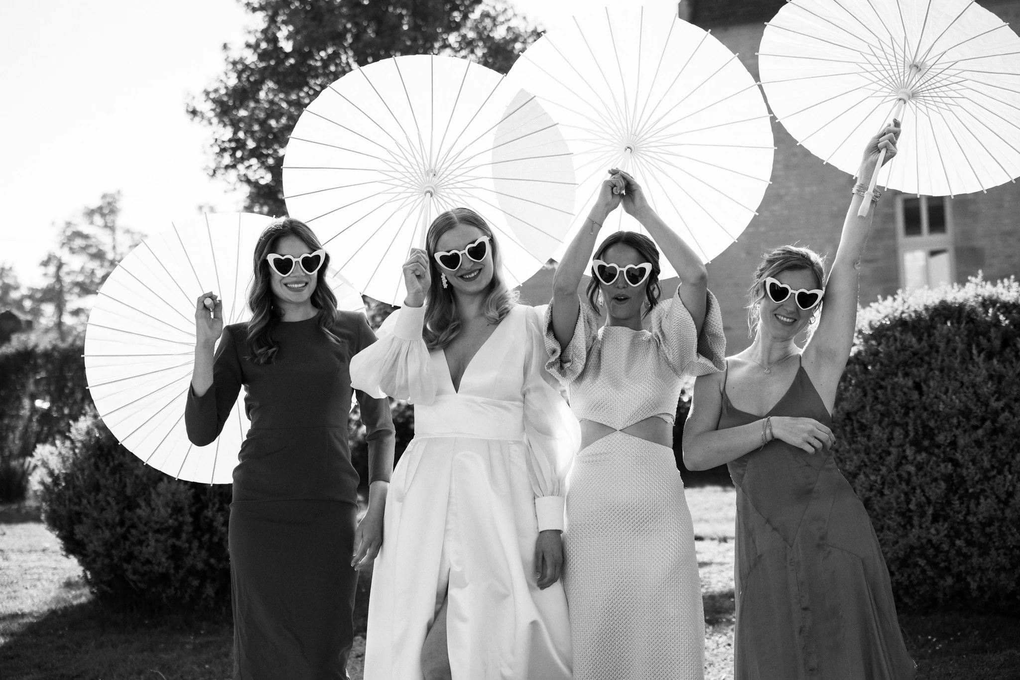 A group of friends celebrates the wedding beneath white parasols