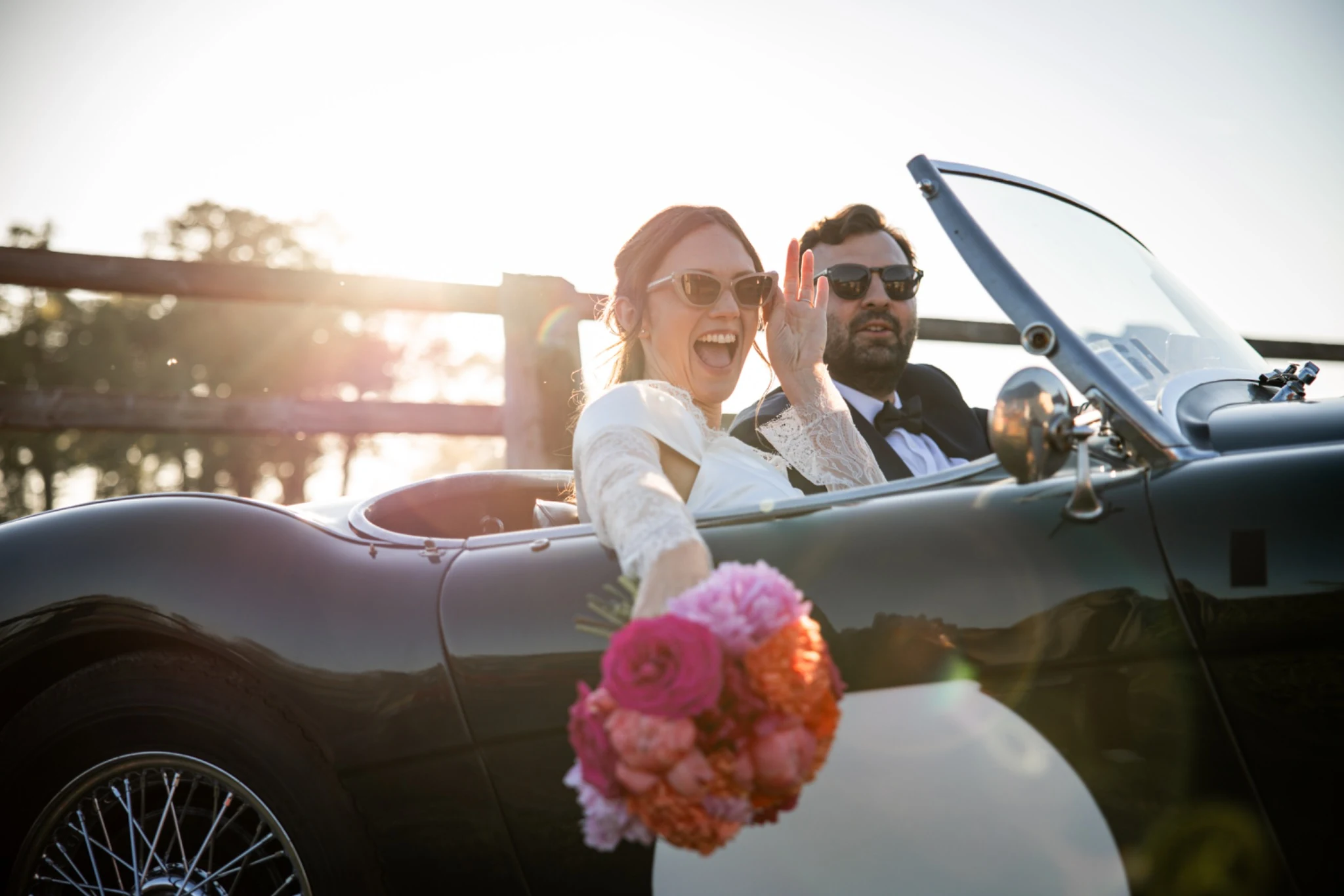 The newlyweds smile together in a convertible
