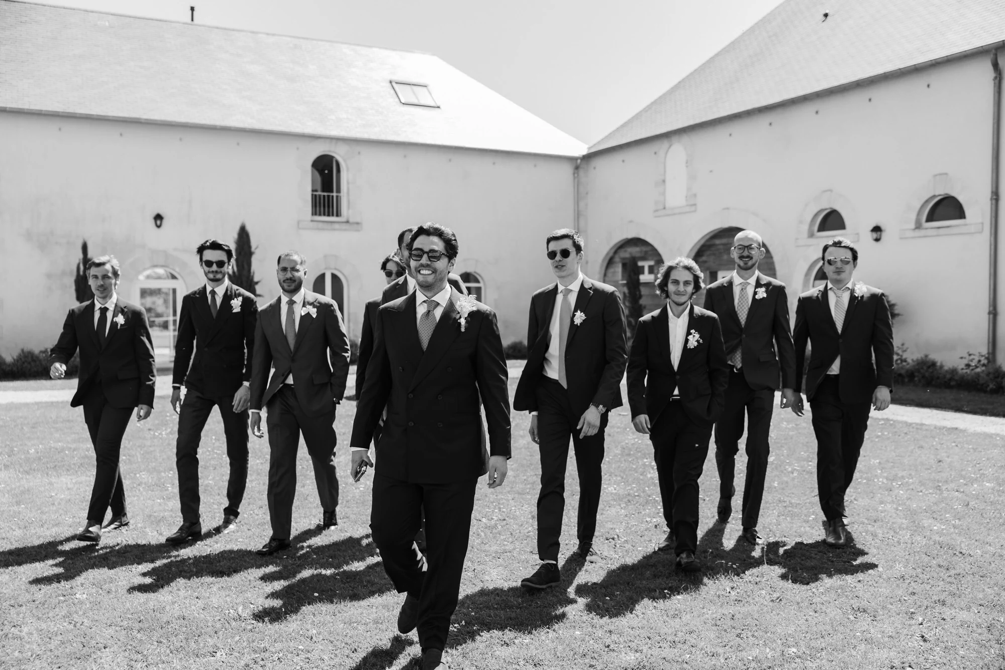 The groom walks with his friends through the venue courtyard